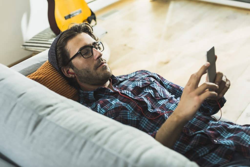 young-man-lying-on-the-couch-hearing-music-with-ea-2022-03-08-01-34-25-utc-1024x683